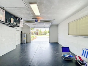 A garage with a concrete floor, a blue folding chair, and a window with blinds.