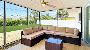 A modern living room with a sectional sofa, a glass coffee table, and a ceiling fan. - Beach House Oasis - Steps from Ocean Access (Venice)