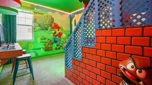 A room with a Mario-themed play area, including a brick wall, a window, and a table with toys. - 6 BD/ 5 BA/ Solara Resort (9038 SR) (Kissimmee)