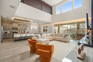 A spacious living area with a large sectional sofa, a kitchen with modern appliances, and a dining area with a glass table. - 6 BD/ 5 BA/ Solara Resort (9038 SR) (Kissimmee)