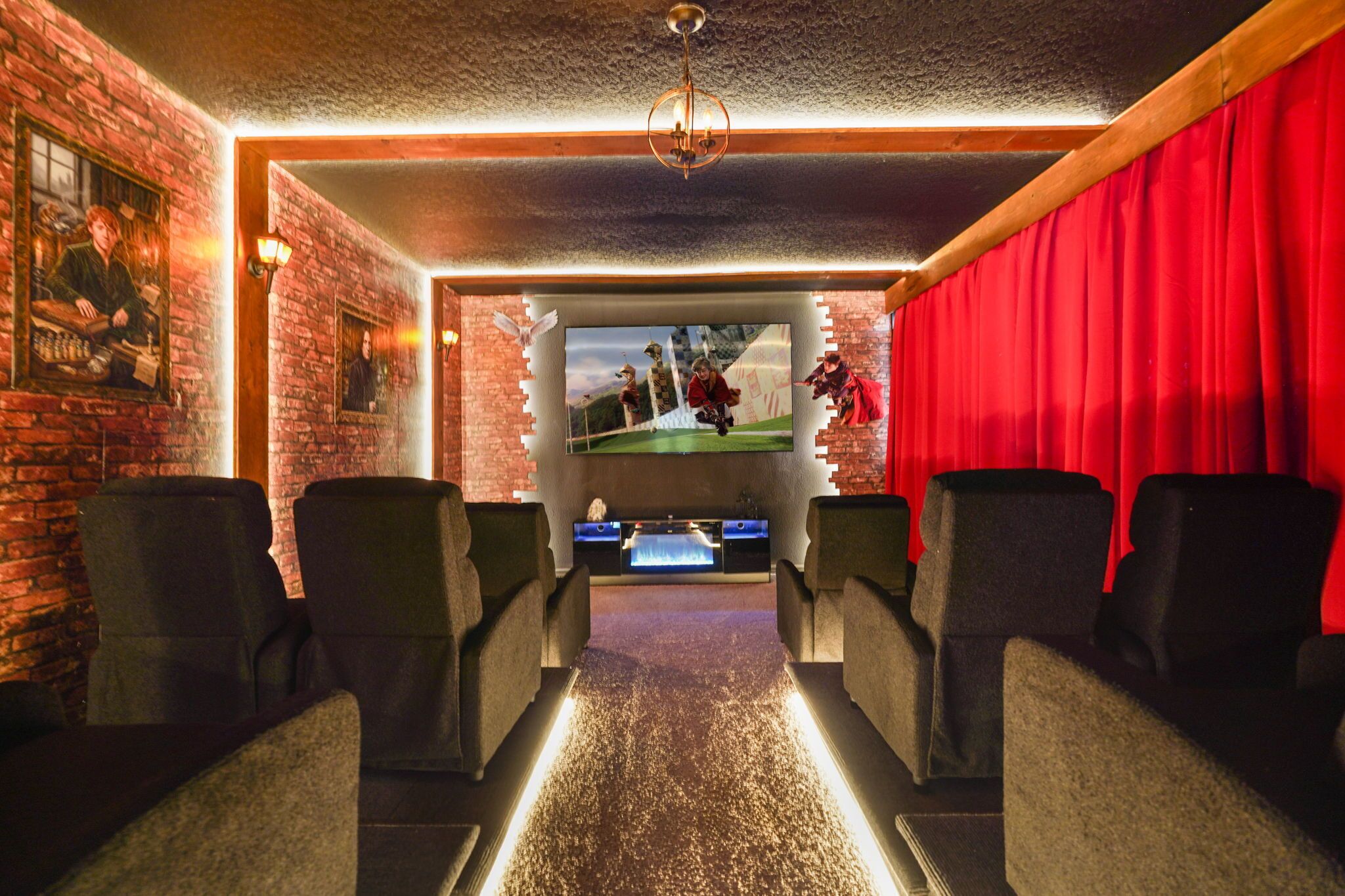 A cinema room with a screen, red curtains, and multiple seats.