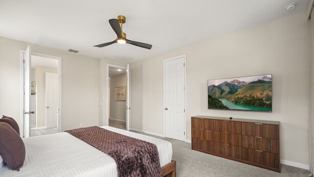 A bedroom with a bed, a dresser, a ceiling fan, and a painting on the wall. - 6 BD/ 5 BA/ Solara Resort (9038 SR) (Kissimmee)