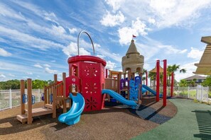A playground with a castle-like structure, slides, and a fenced area. - 6 BD/ 5 BA/ Solara Resort (9038 SR) (Kissimmee)