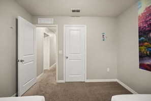 A bedroom with two doors, a hallway, and a wall-mounted picture. - 4 BD/ 3.5 BA/ Compass Bay (3183 TC) (Kissimmee)