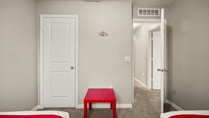 A room with a closed door, a red table, and a carpeted floor. - 4 BD/ 3.5 BA/ Compass Bay (3183 TC) (Kissimmee)