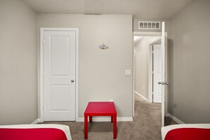 A room with a closed door, a red table, and a carpeted floor. - 4 BD/ 3.5 BA/ Compass Bay (3183 TC) (Kissimmee)