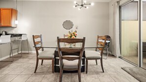 A dining area with a glass table, wooden chairs, a chandelier, and a kitchen in the background. - 4 BD/ 3.5 BA/ Compass Bay (3183 TC) (Kissimmee)