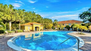 A swimming pool with a tiled deck, surrounded by palm trees and a building with a red-tiled roof. - 4 BD/ 3.5 BA/ Compass Bay (3183 TC) (Kissimmee)