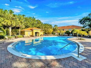 A swimming pool with a tiled deck, surrounded by palm trees and a building with a red-tiled roof. - 4 BD/ 3.5 BA/ Compass Bay (3183 TC) (Kissimmee)