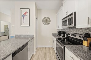 A kitchen with granite countertops, a stainless steel stove, a microwave, and a clock on the wall. - 5 BD/ 4 BA/ Storey Lake (4823 BR) (Kissimmee)