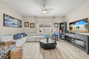 A living room with a sectional sofa, a coffee table, a TV, and a ceiling fan. - 5 BD/ 4 BA/ Storey Lake (4823 BR) (Kissimmee)
