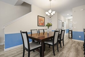 A dining area with a wooden table and chairs, a chandelier, and a painting on the wall. - 5 BD/ 4 BA/ Storey Lake (4823 BR) (Kissimmee)