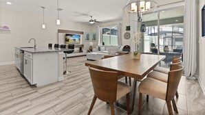 A modern kitchen with a central island, dining area with chairs, and a large window with a view. - 4 BD/ 3 BA/ Storey Lake (3071 GS) (Kissimmee)