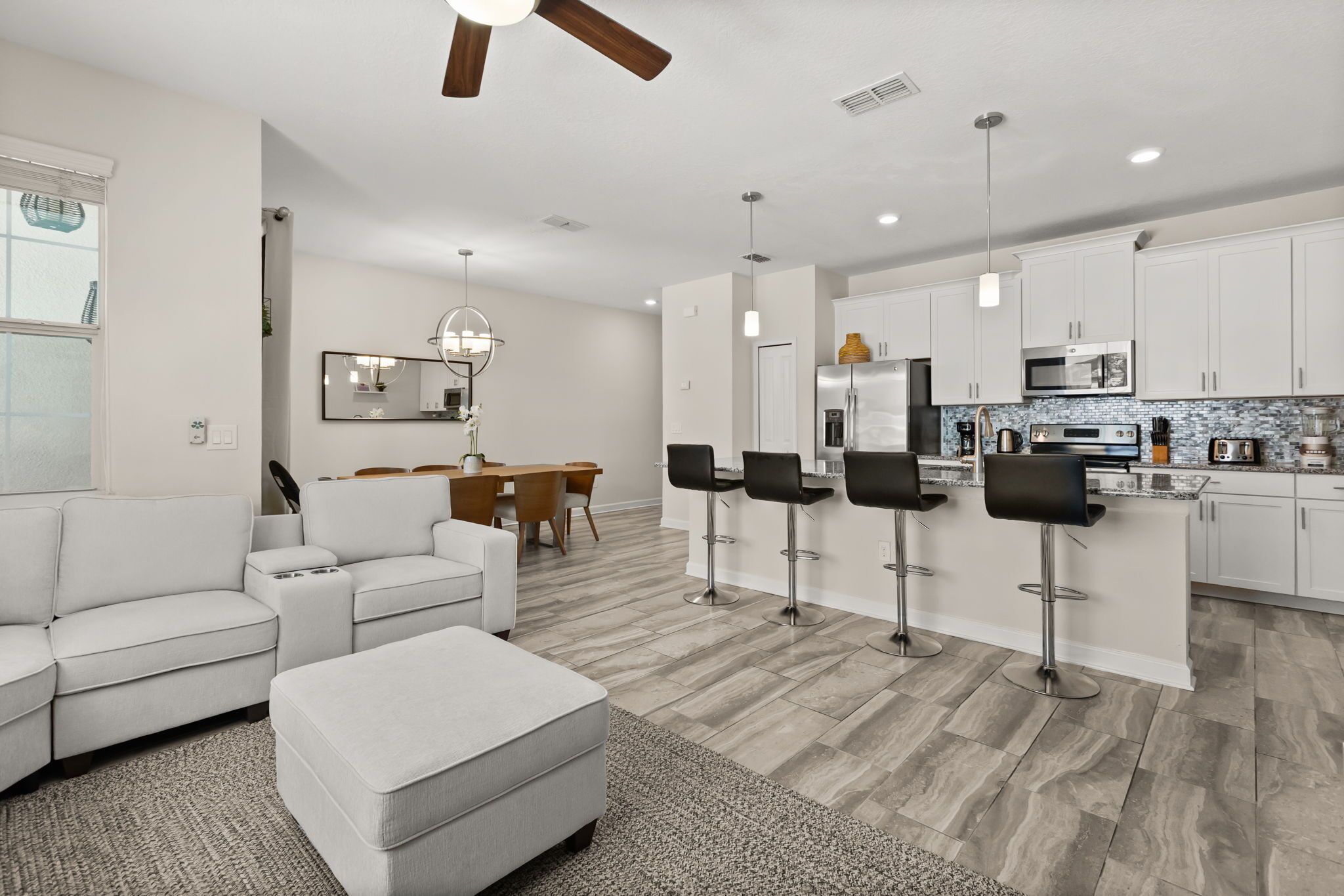 A modern kitchen with white cabinets, a built-in microwave, and a stainless steel refrigerator.