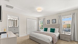 A bedroom with a bed, bedside tables, a dresser, a window with curtains, and a door leading to a bathroom. - 4 BD/ 3 BA/ Storey Lake (3071 GS) (Kissimmee)