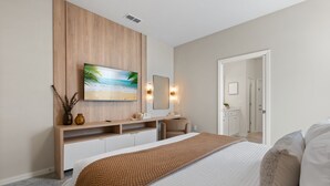 Une chambre à coucher moderne avec un grand lit, une commode en bois, un téléviseur à écran plat et un miroir.