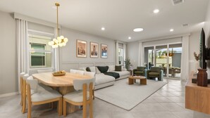 Un salon moderne comprenant un coin repas, un ensemble de canapés, une table basse et un téléviseur posé sur un meuble en bois.
