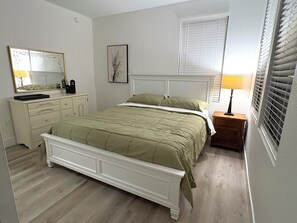 Ein Schlafzimmer mit Bett, Kommode, Spiegel und Nachttischlampe.