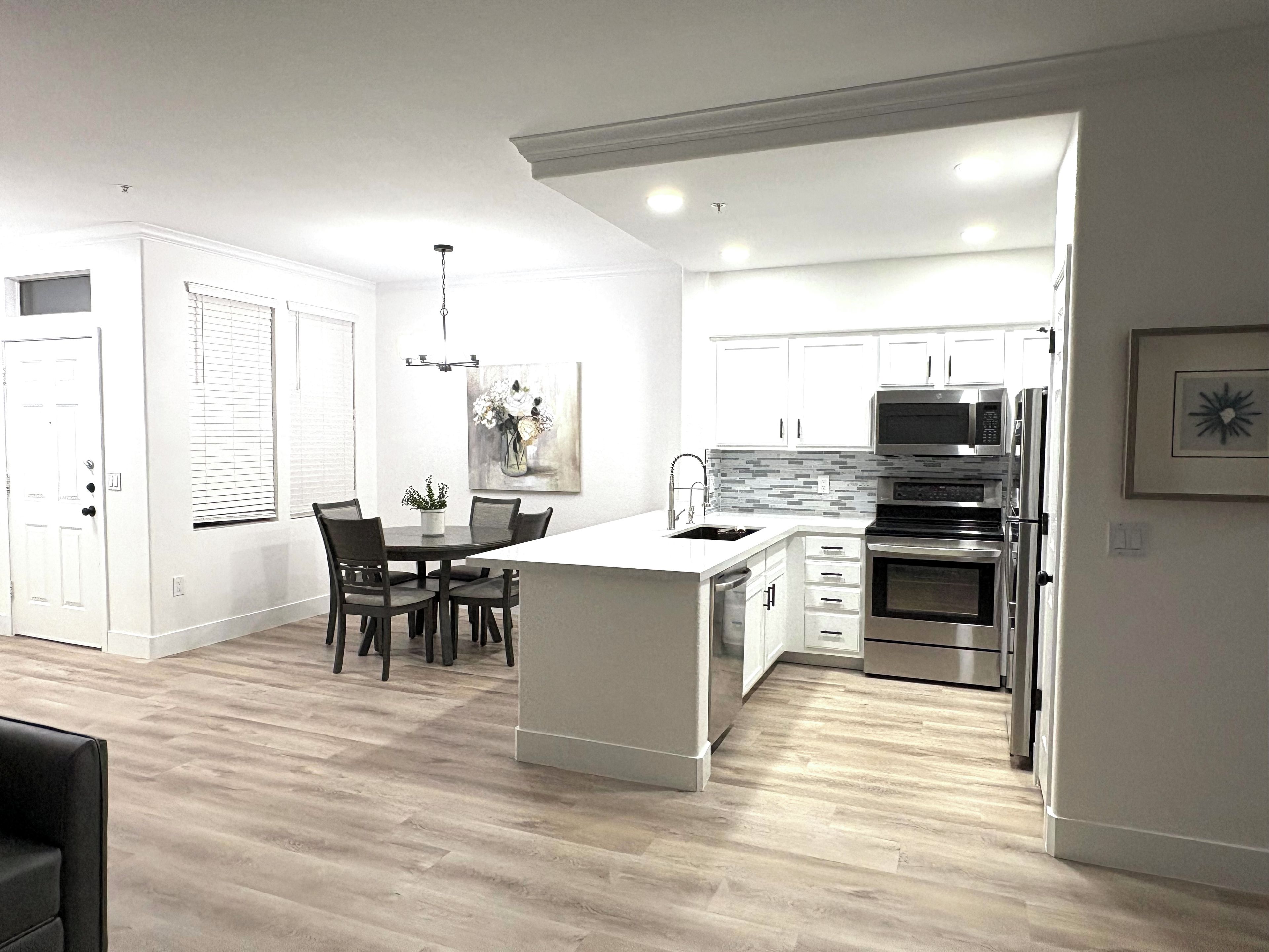 Una cocina moderna con armarios blancos, una isla central y electrodomésticos de acero inoxidable.
