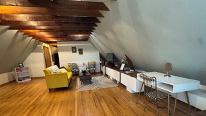 A loft-style room with a wooden floor, a yellow sofa, a white desk, and a metal chair. - Cozy 1 bed,  furnished apartment (Chicago)