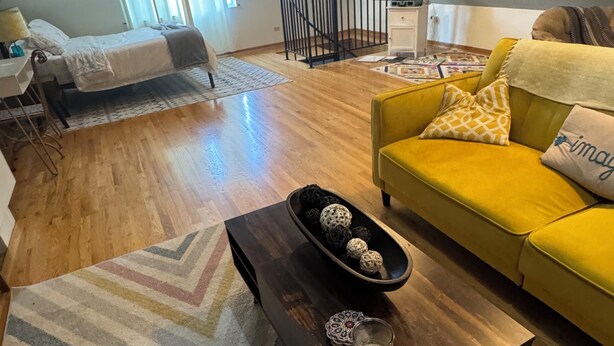 A spacious living area with a yellow sofa, a wooden coffee table, and a patterned rug. - Cozy 1 bed,  furnished apartment (Chicago)