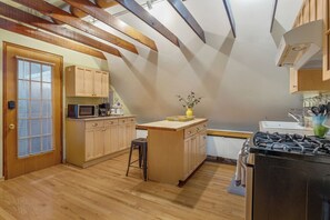 A kitchen with wooden beams, a stove, cabinets, a microwave, and a small island with a vase. - Cozy 1 bed, furnished apartment (Chicago)