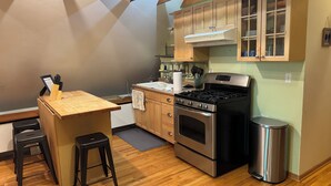 A kitchen with wooden cabinets, a stainless steel stove, and a wooden countertop. - Cozy 1 bed,  furnished apartment (Chicago)