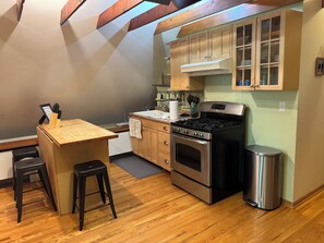 A kitchen with wooden cabinets, a stainless steel stove, and a wooden countertop. - Cozy 1 bed,  furnished apartment (Chicago)