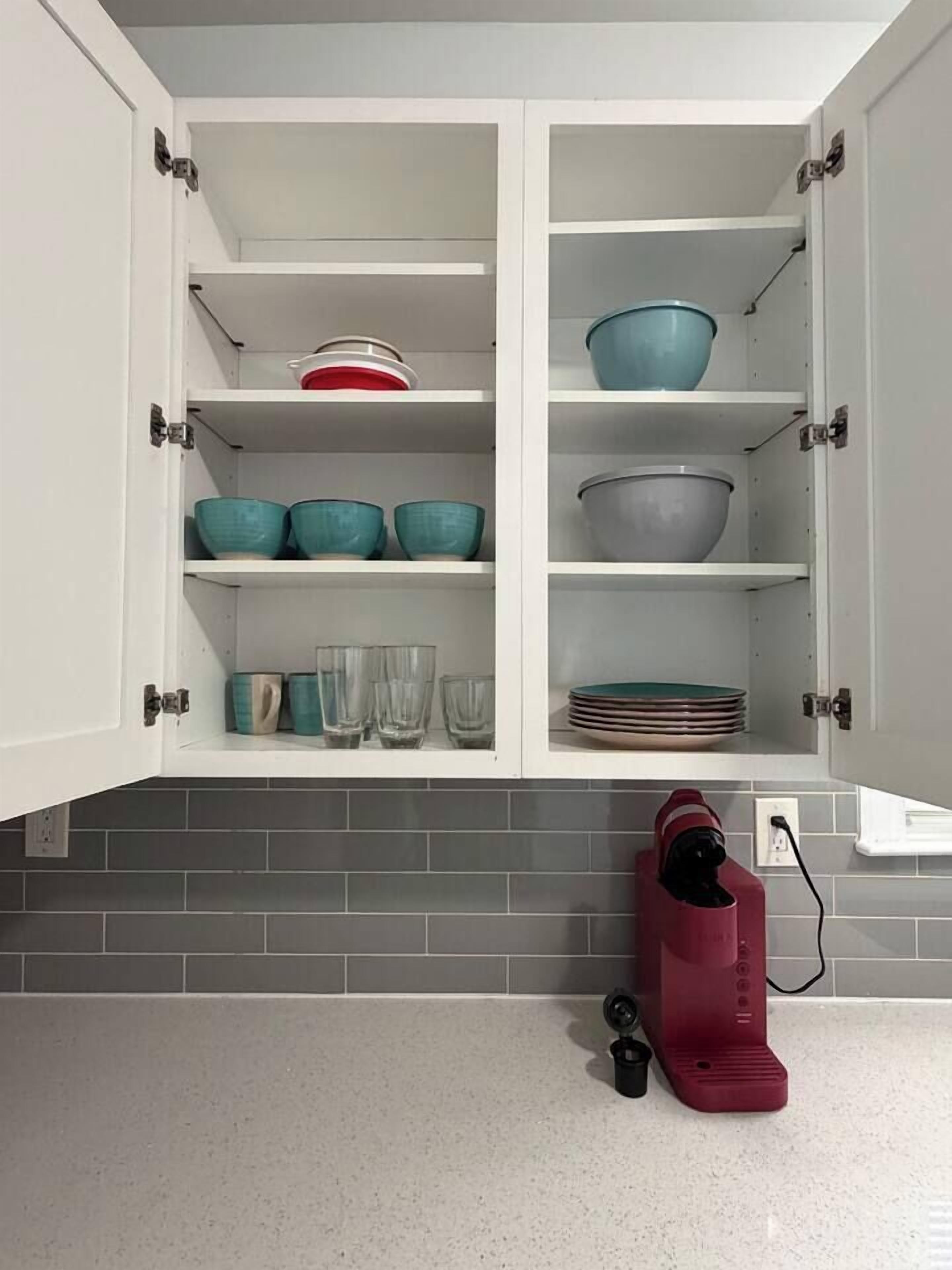 A kitchen with white cabinets, a tiled backsplash, and a red appliance on the counter.