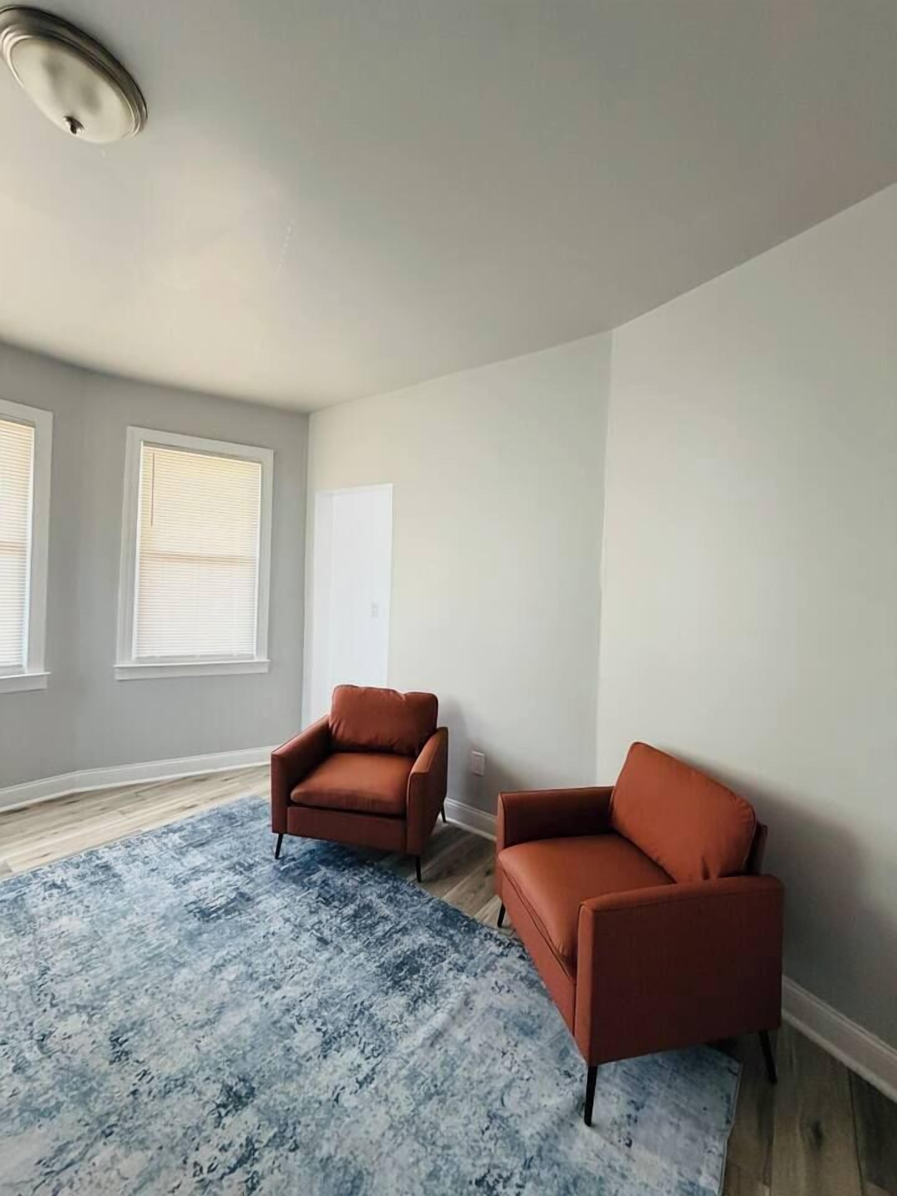A room with two brown armchairs, a blue patterned rug, and a white door.