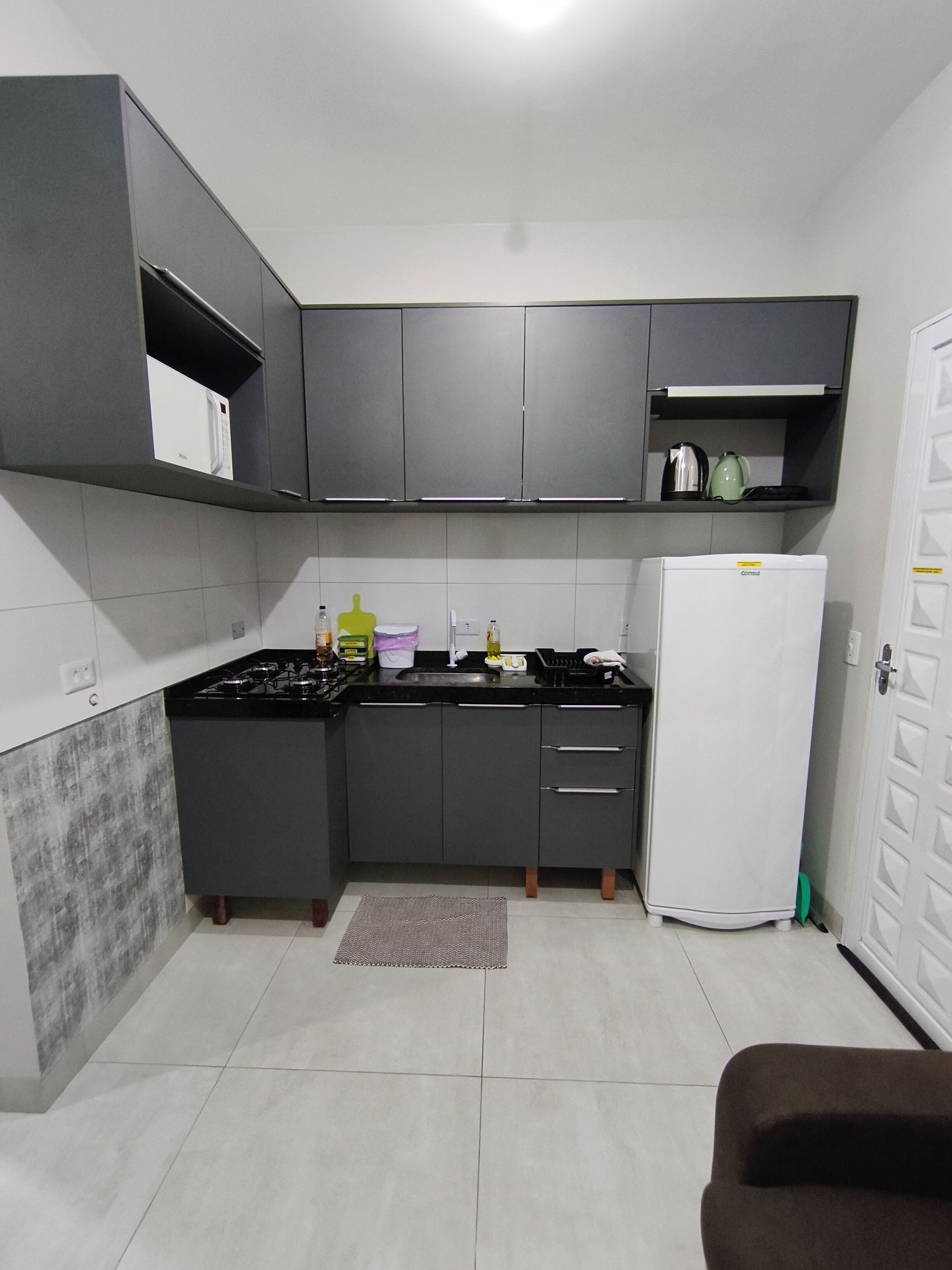 A compact kitchen with grey cabinets, a white refrigerator, and a gas stove.
