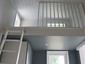 Ein Zimmer mit Fenster, weißer Brüstung und Decke mit Holzbalken.