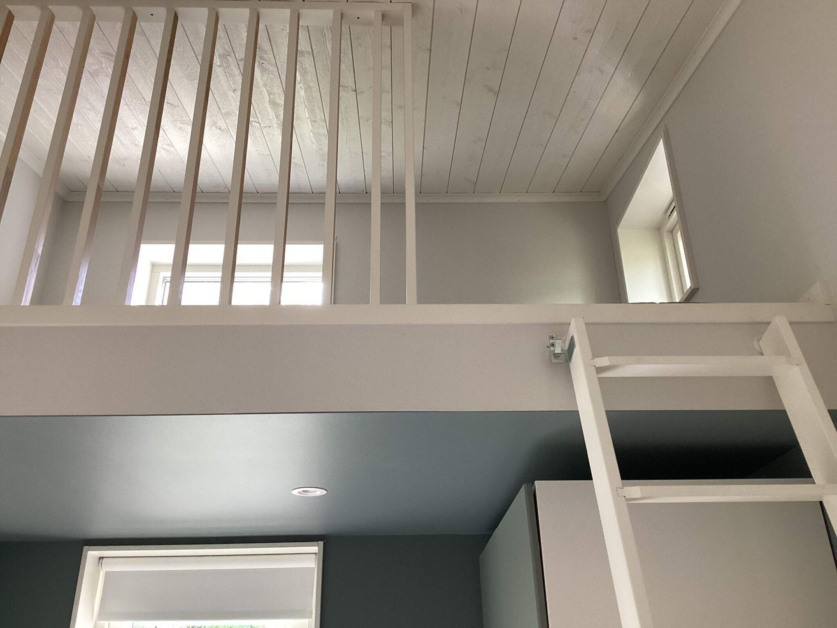 Una habitación con un altillo, una ventana y una puerta.