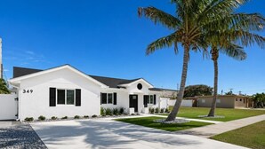 A modern two-story house with a white exterior, numbered 349, featuring a front yard with a palm tree, a driveway, and a well-maintained lawn. - 🏖️3BD/2BA Walk to Beach & Downtown / Pool / 349NO (Cocoa Beach)
