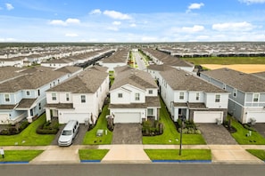 A row of single-family homes with attached garages, a well-maintained lawn, and a clear sky. - 6 BD/ 4.5 BA/ Windsor Island (3763 LA) (Davenport)