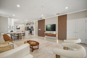 A modern living room with a dining area, kitchen, and a large flat-screen TV mounted on the wall. - Luxury 6BD/4.5BA Windsor Island (3763 La) (Davenport)
