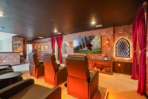 Una sala de cine con butacas reclinables de cuero, una pantalla y una pared de ladrillo.