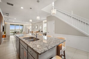 A modern kitchen with a granite countertop, stainless steel sink, and pendant lighting. - Luxury 6BD/4.5BA Windsor Island (3763 La) (Davenport)
