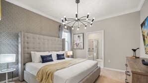 Ein Schlafzimmer mit einem großen Bett, einer Kandelaber, einem Schreibtisch und einer Kommode.