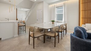 A modern kitchen with a central island, a dining area with a round table and chairs, and a staircase leading to another level. - 7 BD/ 5.5 BA/ Windsor Cay (1095 OP) (Clermont)