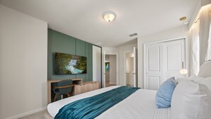 A bedroom with a bed, a desk, a chair, and a painting on the wall. - 7 BD/ 5.5 BA/ Windsor Cay (1095 OP) (Clermont)