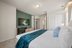 Ein Schlafzimmer mit einem Bett, einem Schreibtisch, einem Stuhl und einem Bild an der Wand.