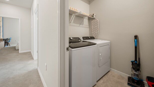 A laundry room with a front-loading washer and dryer, a ceiling fan, and a vacuum cleaner. - 7 BD/ 5.5 BA/ Windsor Cay (1095 OP) (Clermont)