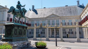 A statue of a figure on horseback in front of a large building with a gated entrance.