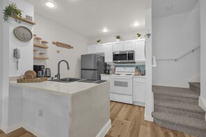 Een moderne keuken met witte kasten, roestvrijstalen apparatuur en een centraal eiland.
