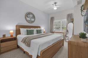 Een slaapkamer met een bed, nachtkastjes, een raam met gordijnen en een schilderij aan de muur.