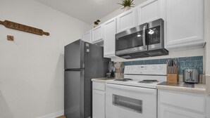 A compact kitchen with white cabinetry, a stainless steel refrigerator, a microwave, and a stove. - 3 BD/ 2 BA/ Villas at Seven Dwarfs Lane (31-106) (Kissimmee)