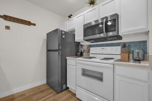 A compact kitchen with white cabinetry, a stainless steel refrigerator, a microwave, and a stove. - 3 BD/ 2 BA/ Villas at Seven Dwarfs Lane (31-106) (Kissimmee)