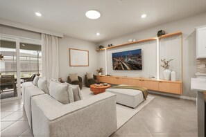 Een moderne woonkamer met een zithoek, een salontafel en een stadsgezichtschilderij aan de muur.