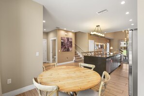 A modern kitchen with a central island, wooden dining table, and chairs. - 4 BD/ 4.5 BA/ Magic Village Views (7478 BD) (Kissimmee)